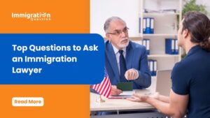 An immigration lawyer in a suit sitting at a desk talking to a client, with the Immigration Question logo and a headline stating 'Top Questions to Ask an Immigration Lawyer.'